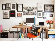 An inspirational gallery wall by Beth Diana Smith features quotes, photos and art, while storage bins placed around the floor’s perimeter and a wooden side table provide space for files and paperwork. 