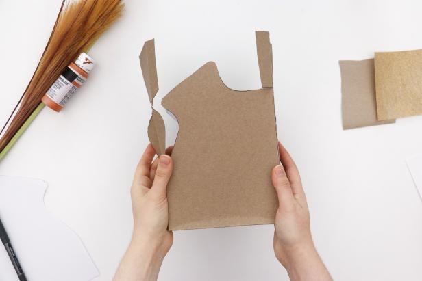 Cut the shape out from the front and back of the box, leaving the sides of the box intact and with tabs on either side.