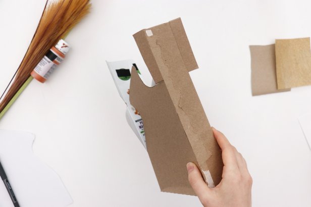 Cut the shape out from the front and back of the box, leaving the sides of the box intact and with tabs on either side.