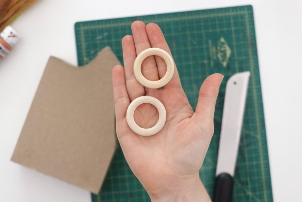 Use small wooden rings as handles. Use a saw to cut them down into an arc, and then sand the ends until the angles let them lay flush against the curves of the vase. Hot glue them in place.