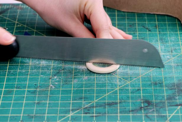 Use small wooden rings as handles. Use a saw to cut them down into an arc, and then sand the ends until the angles let them lay flush against the curves of the vase. Hot glue them in place.
