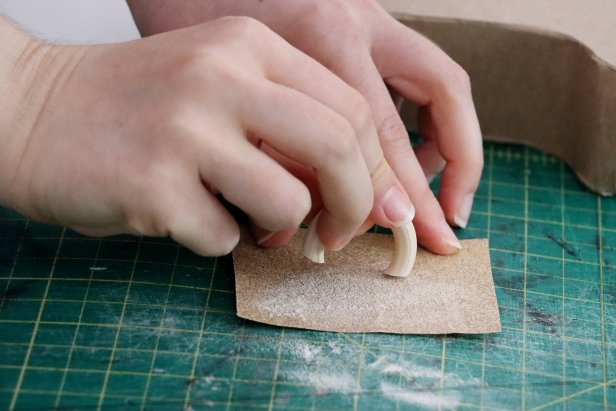 Use small wooden rings as handles. Use a saw to cut them down into an arc, and then sand the ends until the angles let them lay flush against the curves of the vase. Hot glue them in place.