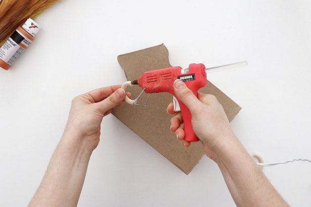 Use small wooden rings as handles. Use a saw to cut them down into an arc, and then sand the ends until the angles let them lay flush against the curves of the vase. Hot glue them in place.