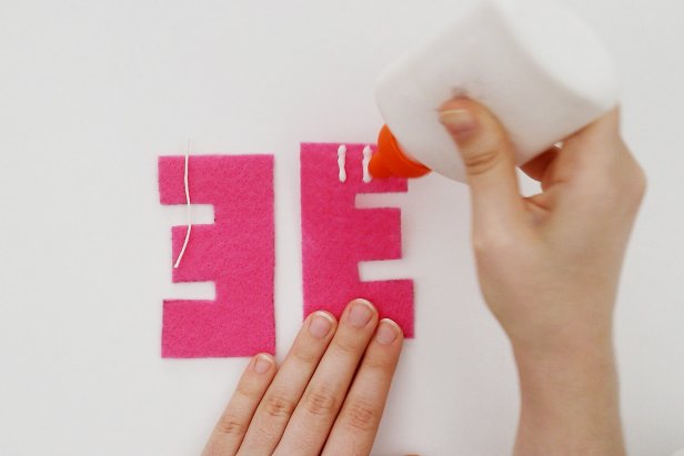 Cut a piece of light-colored string measuring an inch or two. Add two lines of glue to the back letter and press the string into place to make a hanger. Let dry.