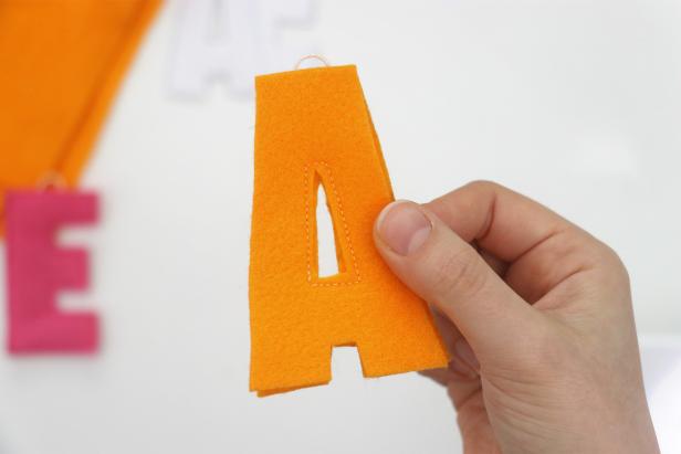 Of course, some letters will be easier than others. If your letter has an inside shape like A, sew that first before sewing around the outside. If the letter has curves like R, S, or “&”, be extra careful sewing around them, taking your time to keep your border size as even as possible around the entire shape. If your letter has two stems at the top like V or H, add a hanger to each stem so that the letter hangs evenly.