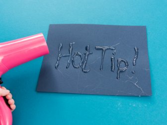 Woman Uses Hair Dryer to Remove Glue Wisps From Project