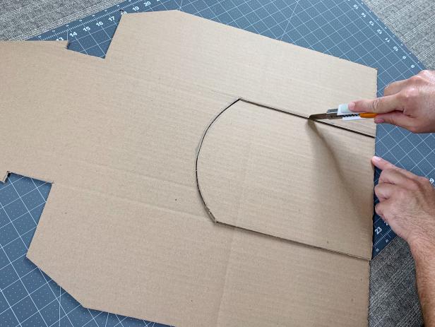 Use a craft blade to carefully cut out the outline of the house. Once done, place the cut house onto the second piece of cardboard and trace it. Cut out a second façade and put it aside for later.