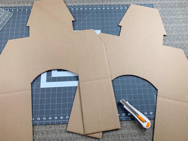 Use a craft blade to carefully cut out the outline of the house. Once done, place the cut house onto the second piece of cardboard and trace it. Cut out a second facade and put it aside for later.