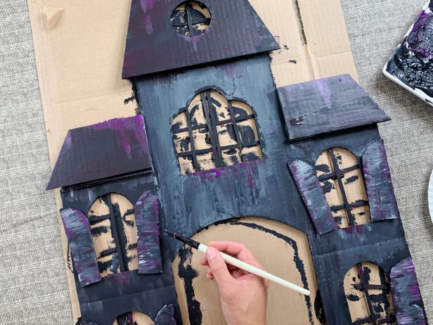 Add a base coat of black acrylic paint to the house making sure to get all the nooks and crannies. While the paint is still wet add texture by mixing in different colors and sloppily painting them on. Tip: Drag a semi dry brush down from window edges and roof tops to create a weathered look.