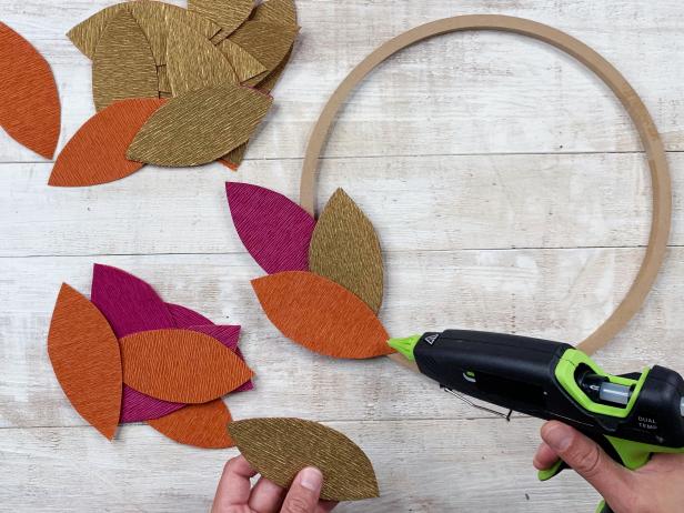 Add a little hot glue to the bottom of each leaf and carefully layer and place the leaves around the wreath ring with the leaves going in the same direction for a continuous flow. Tip: Alternate colors while working for an organic and colorful look.