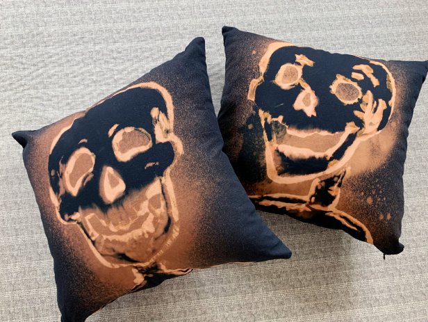Two black pillows with orange skeleton outlines