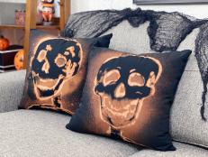 Two black pillows with orange skeleton outlines on gray sofa