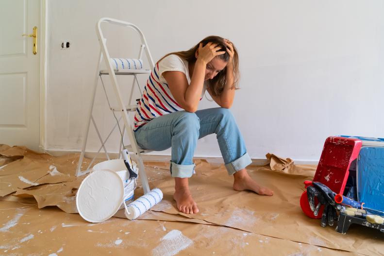 Stressed Young Woman Looks At The Floor In An Unpainted Room