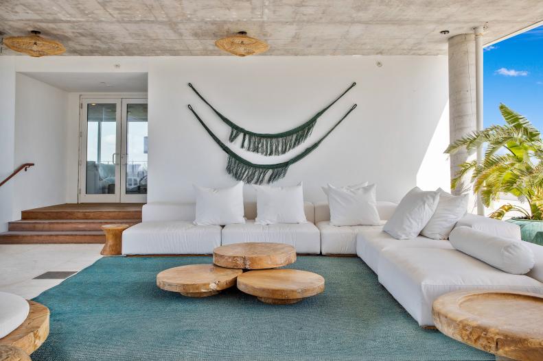 White room with concrete ceiling, teal area rug and round wood tables.