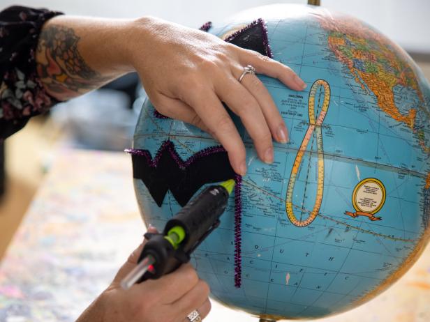 Step 4. Using hot glue and pipe cleaners, trim the felt features on the globe. Use scissors to trim pipe cleaners.