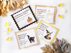 Flat Lay of Four Printed Halloween Scavenger Hunt Cards Featuring a Pumpkin, Cat, Witch and Mummy, Surrounded by Candy and Fall Leaves