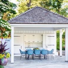 White Coastal Poolhouse With Blue Chairs