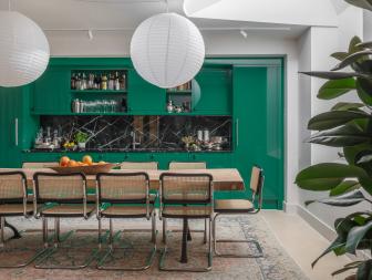 A wooden dining table in front of green kitchen cabinets