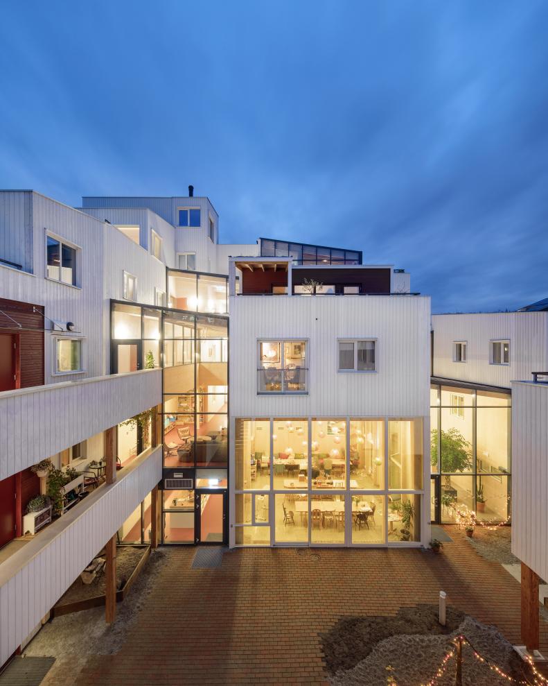An exterior shot of the courtyard of a gray, boxy cohousing structure