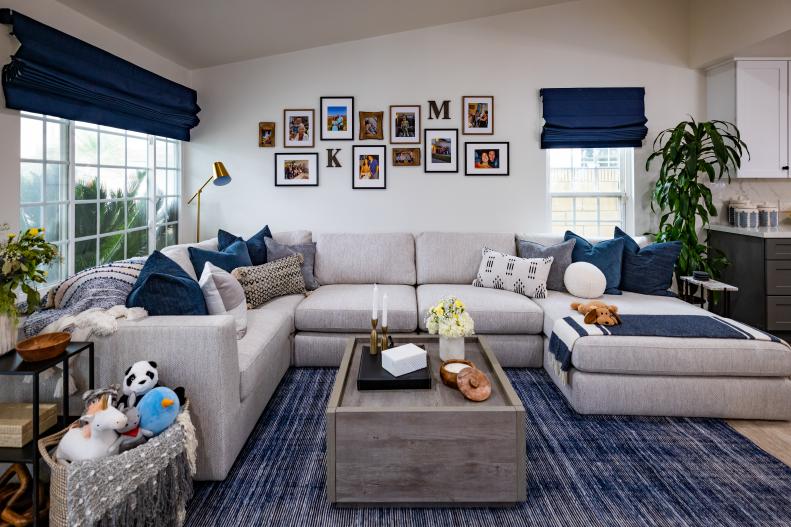 After - Drew and Jonathan have removed the wall between the living and dining rooms, and created an open yet cozy space with a large grey sectional and blue accents, as seen on Property Brothers: Forever Home.