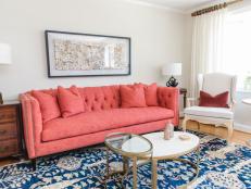 White living room with blue area rug, oval table and pink sofa.