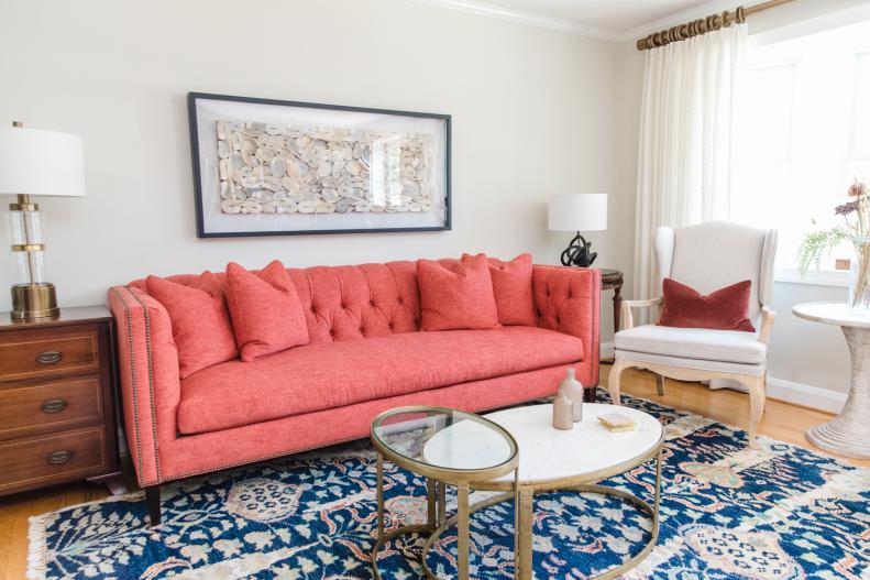 White living room with blue area rug, oval table and pink sofa.
