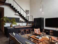 An open-concept living room with vintage furniture, metal stairs