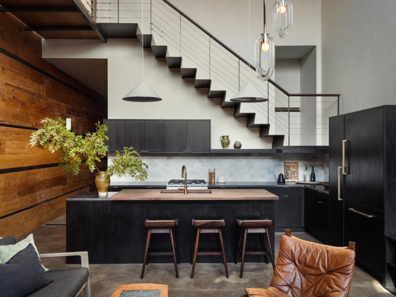 Open plan kitchen with soft leather chair and metal staircase