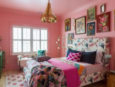 A guest room with a bed, a gallery wall, and pink walls and ceiling