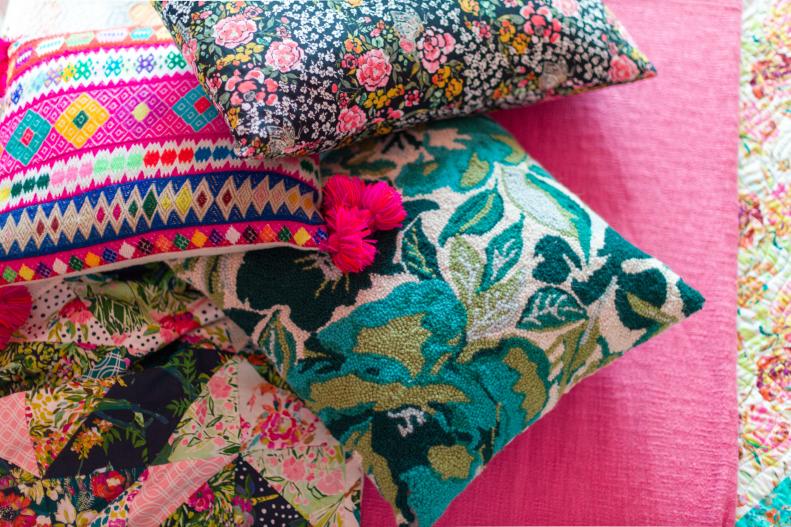 Three pillows with different prints lay on a bed 