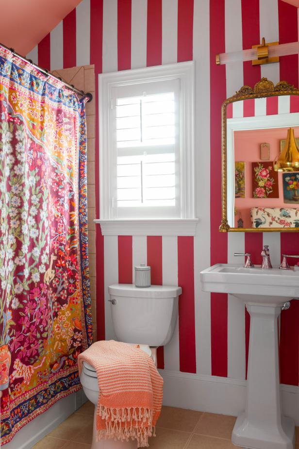 A bathroom with vertically striped walls and pink painted ceiling