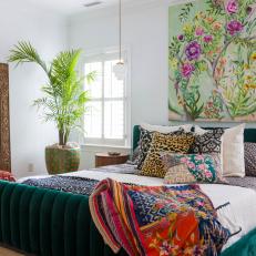 A Primary Bedroom with Emerald Green Bed and Large Floral Painting
