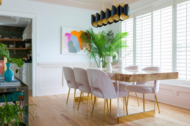 Six-seat table and chairs in a bright dining room with art and plants