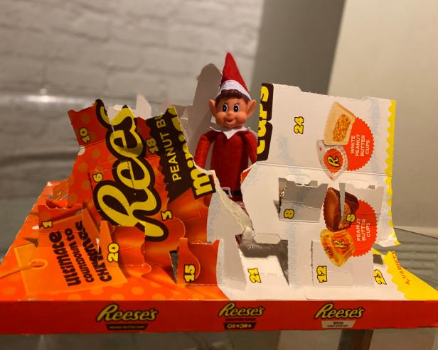 Oxted, Surrey, UK - December 21 2019 - Naught Elf on the shelf eating Reeses pieces from an advent calendar