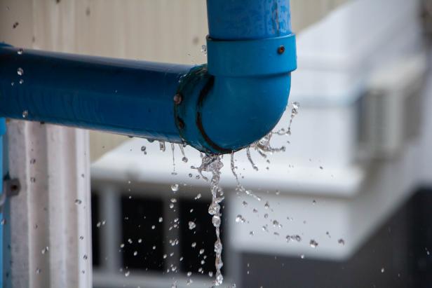 Closeup view of leaked and splash water from the plastic pipe during the rainy day after storm