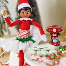 A toy elf holds a tiny gingerbread cookie. 