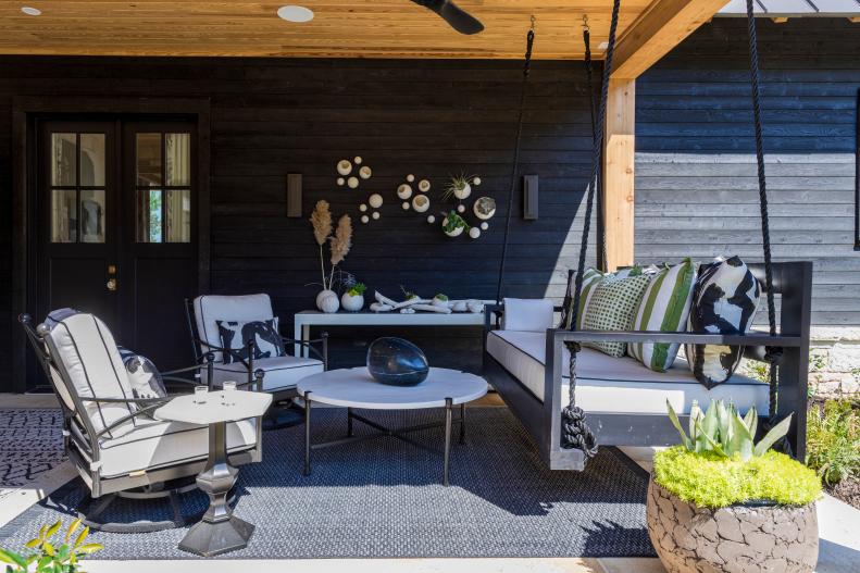 Black exterior paneling with white chairs and table. 