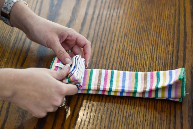 The next step in folding this napkin to resemble a Christmas gift is to turn the strip and accordion fold once more.