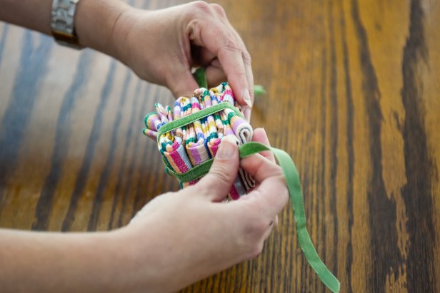 The next step in this Christmas gift napkin folding technique is to secure the cube shape by tying a ribbon around it.