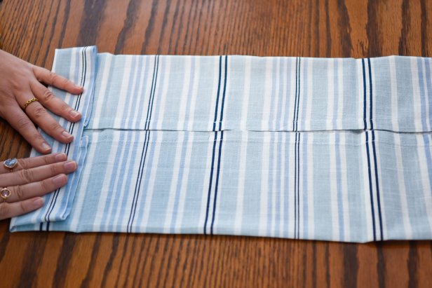 The next step in turning this cloth napkin into a holiday star is to turn the folded napkin and accordion fold into a short strip.