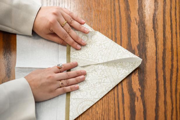 The next step in creating this Thanksgiving turkey paper napkin fold is to fold the top corners down.