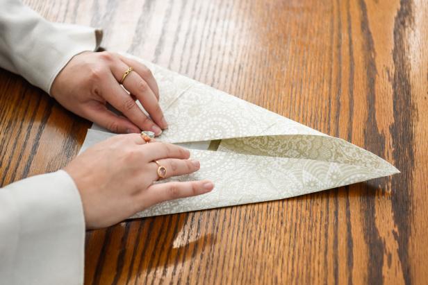 The next step in creating this Thanksgiving turkey paper napkin fold is to fold the sides inward to create a triangle.