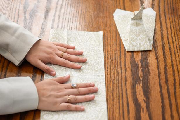 The next step in creating this Thanksgiving turkey paper napkin fold is to fold the second napkin in half.
