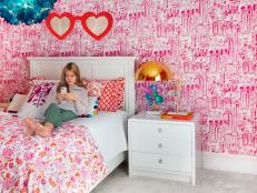 This teen girl's bedroom features pink wallpaper and bedding.