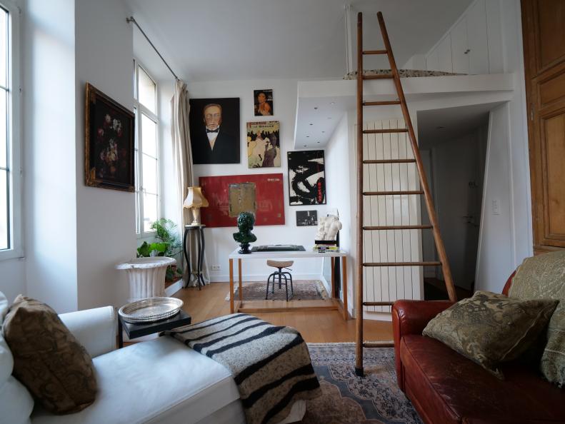 A living room with small lofted sleeping area above the entryway.