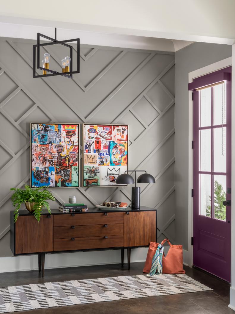 This gray entryway features a purple front door, accent wall and modern lighting.