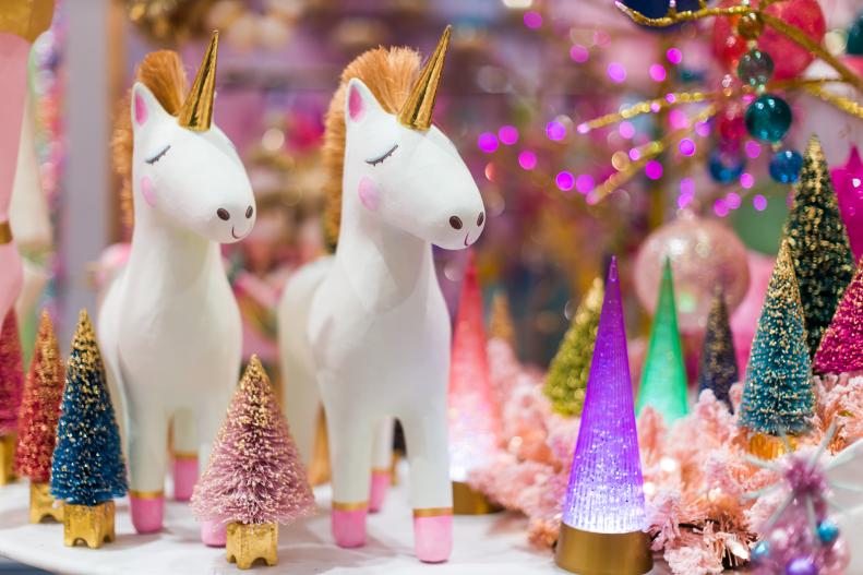 Paper mache unicorns stand on display beside glowing glittery trees