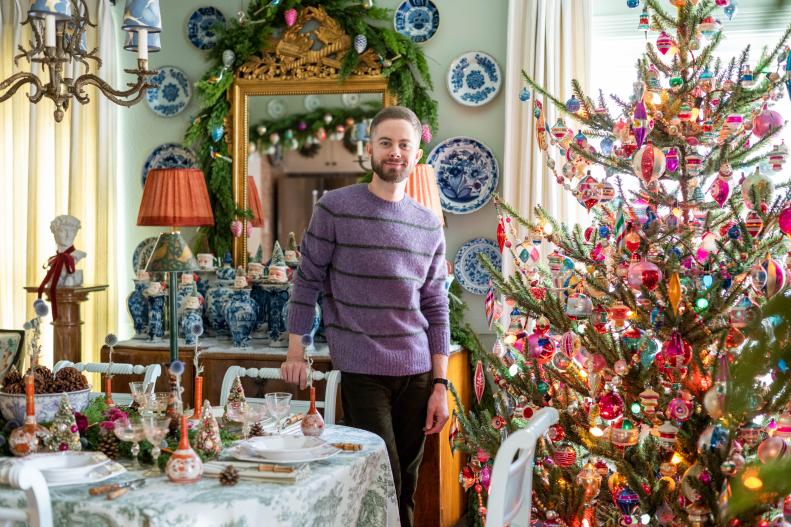 Leben smiles to camera standing beside his colorful vintage tree