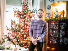 Man smiles standing beside multi-color Christmas tree in dining room