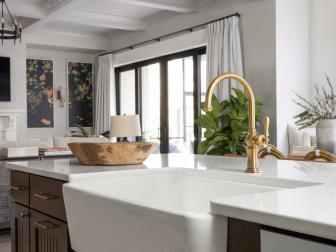 The kitchen’s farmhouse sink has a large, single bowl that accommodates large pots and pans, and a sleek apron that brings a modern, clean-line aesthetic. The sink’s faucet displays vintage style, with a high-arc spout and turned lever handle. 